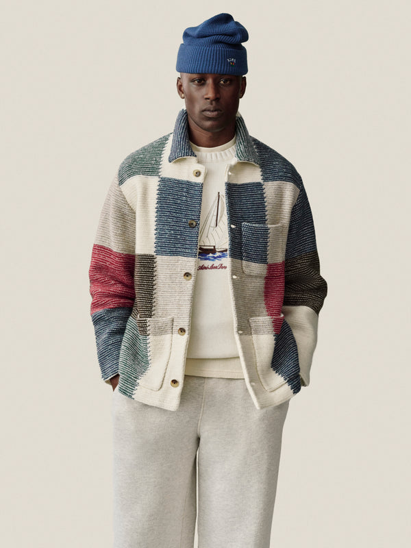 Man in a blue beanie, patchwork jacket, and Stone Washed Marina Sweatpants stands against a plain background.