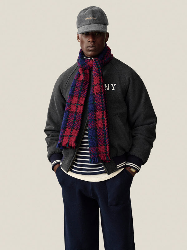 A man wears the Striped Crest Quarter Zip, gray cap, blue pants, and a red and blue plaid scarf facing forward.