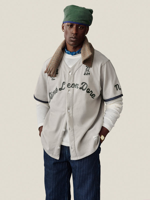 Man in a Mulberry Chainstitch Baseball Jersey and striped pants stands against a plain background.