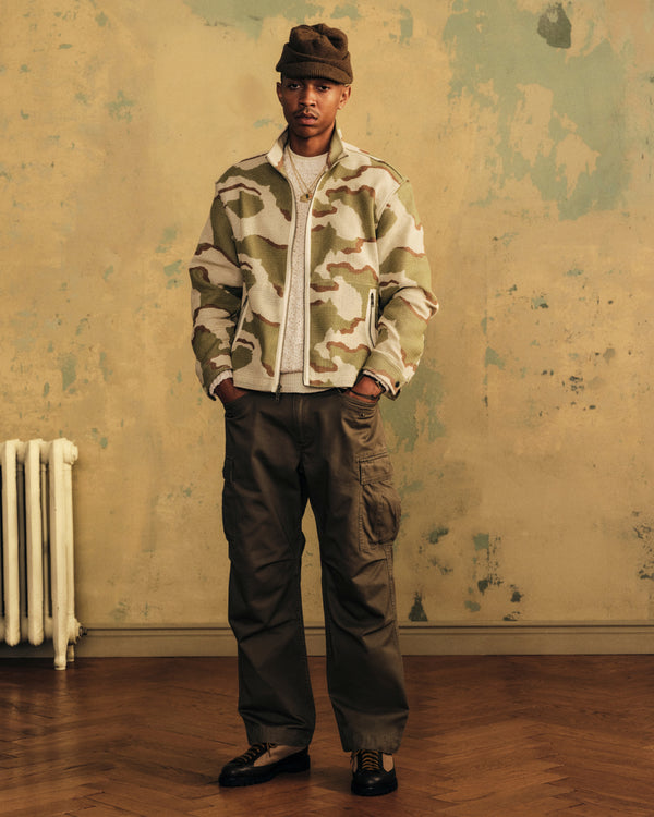 Man wearing a Camo Mesh Zip Overshirt over a white sweater with cargo pants.