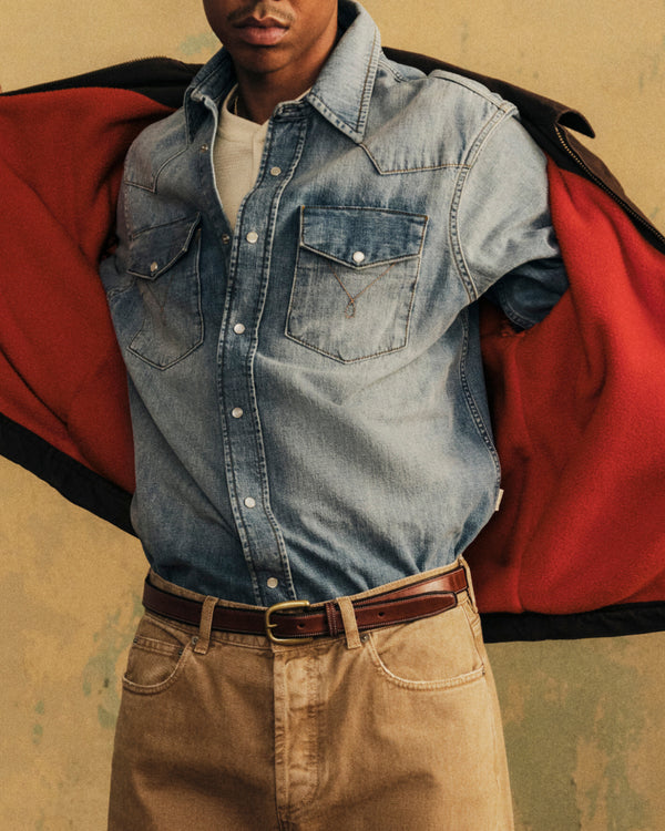 A person wears a light blue Denim Western Shirt with snap buttons and two chest pockets.