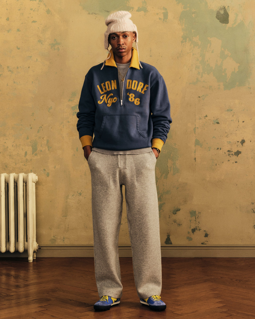 A person wearing a navy Chainstitch ’86 Half Zip Pullover with yellow trim and yellow LEON DORE Nyc 86 embroidery.