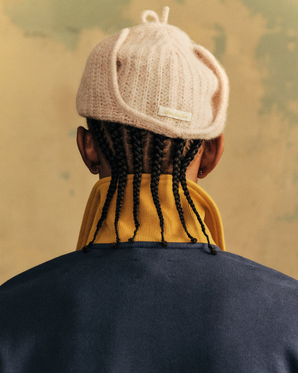 Back view of a person wearing a pale pink Alpaca Wool Knit Earflap Hat with a small rectangular tag on the back.