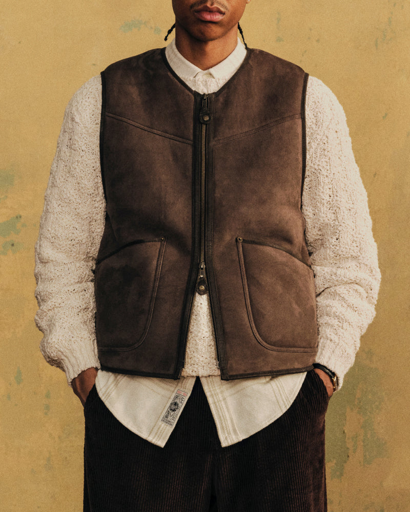 A person wearing a brown Shearling Biker Vest over a white sweater and collared shirt.
