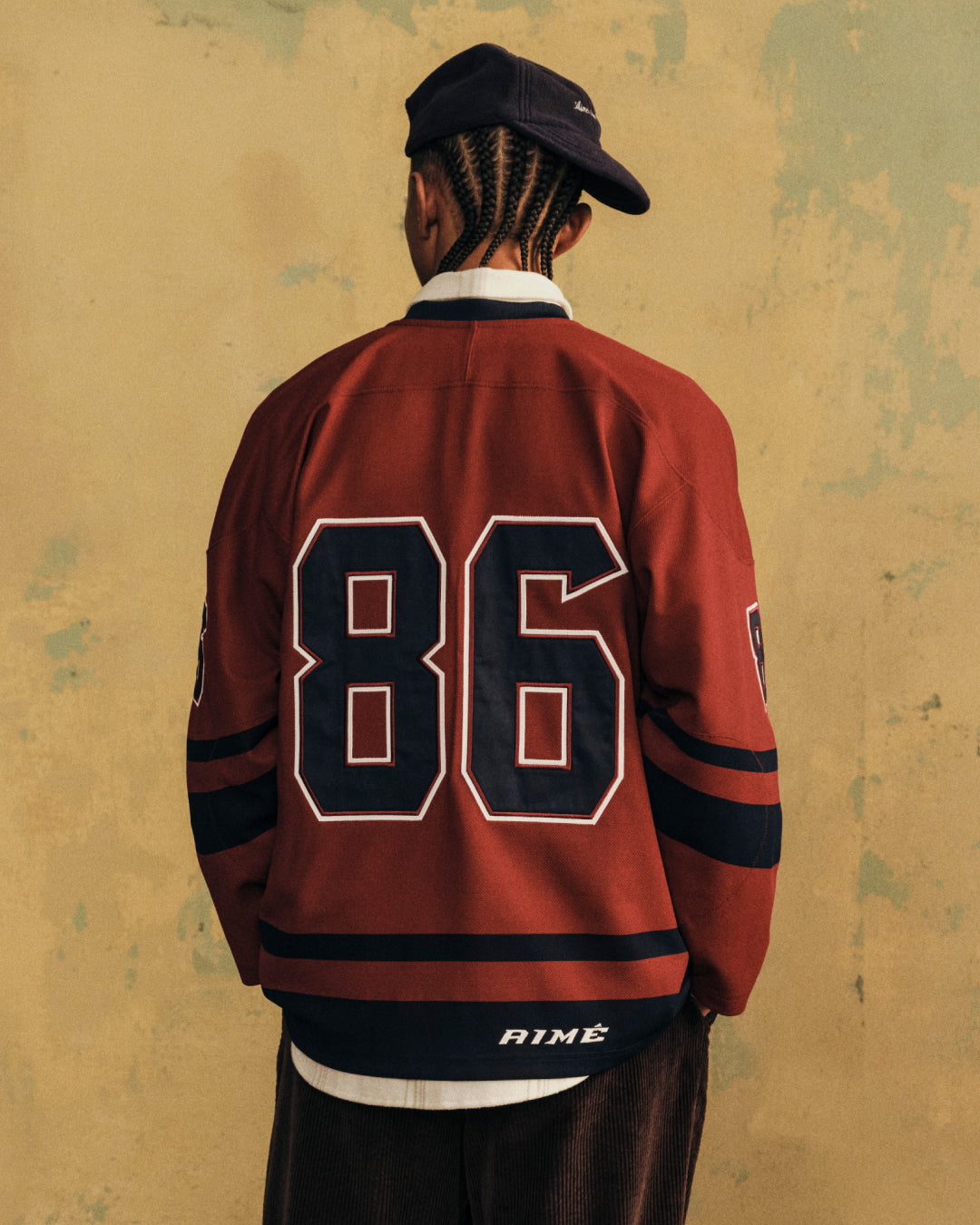 A person seen from behind wearing a red Team Aimé Hockey Jersey with the number 86 on the back.