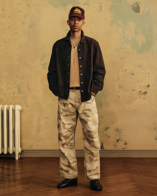 A man wearing a dark brown Suede Overshirt over a beige sweater and camouflage cargo pants.