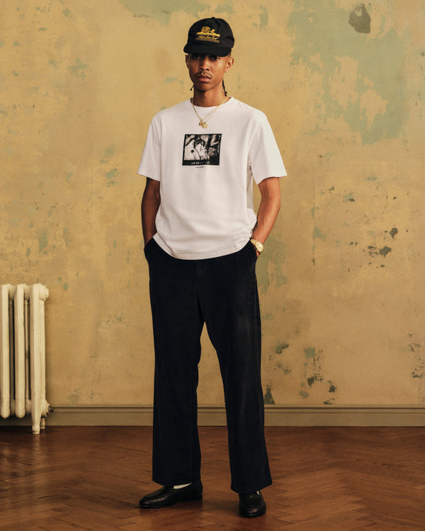 A man wearing The Esco Tee, dark trousers, and a black baseball cap.