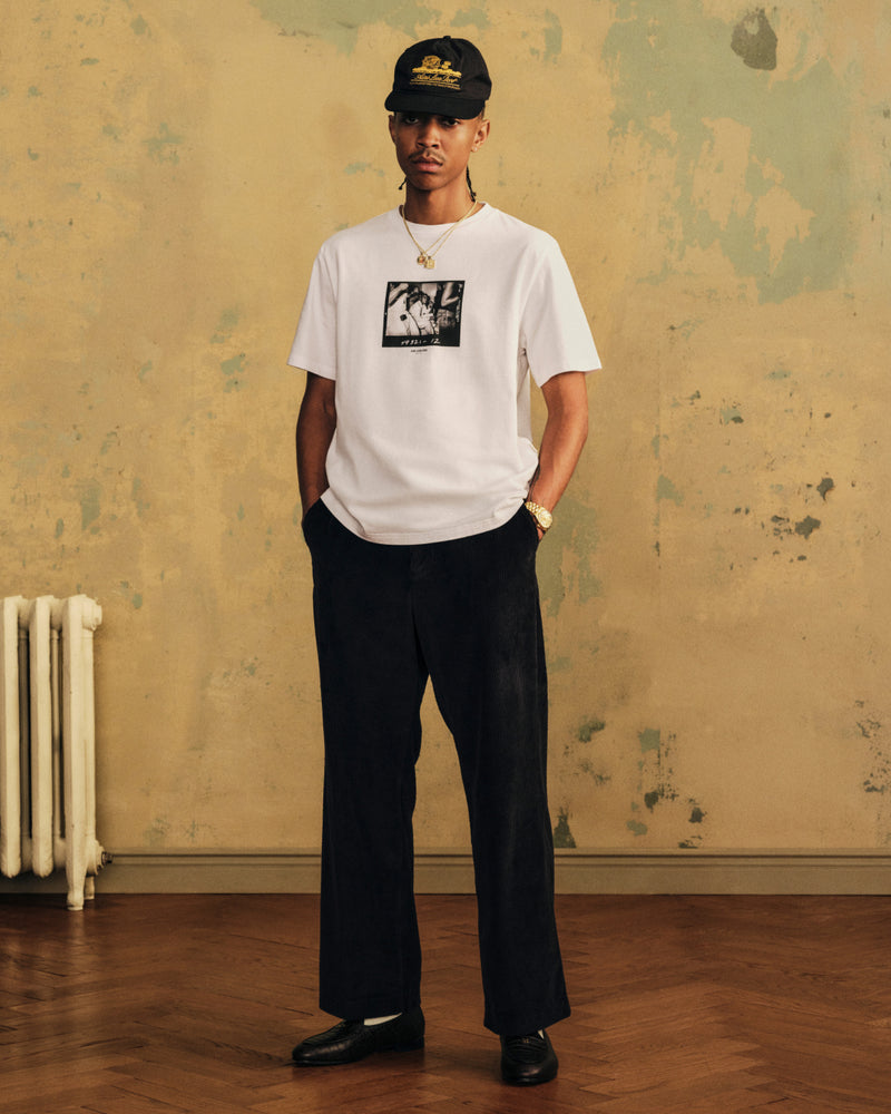 A man wearing The Esco Tee, dark trousers, and a black baseball cap.