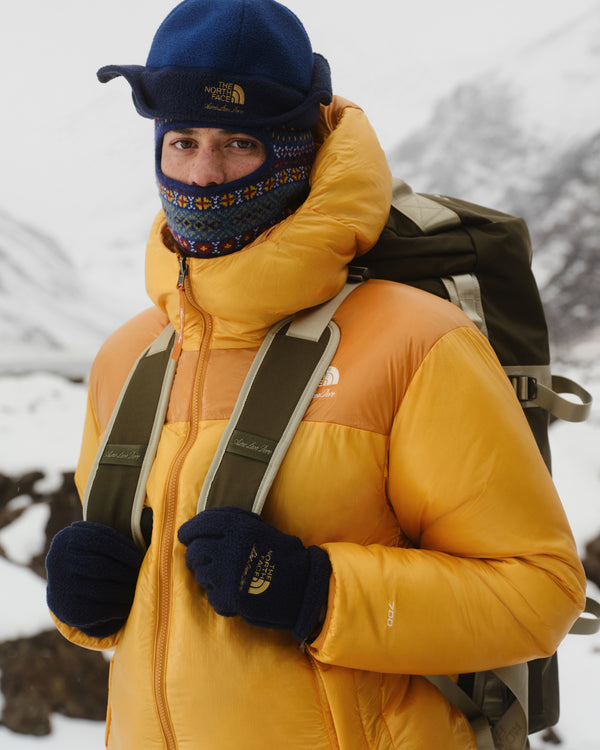 A person wears the ALD / The North Face Fair Isle Balaclava, standing in a snowy mountain landscape.