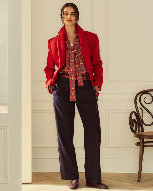 Woman in a red blazer, patterned pussy-bow blouse, and dark trousers wearing Snake Print Leather Ballet Flat.