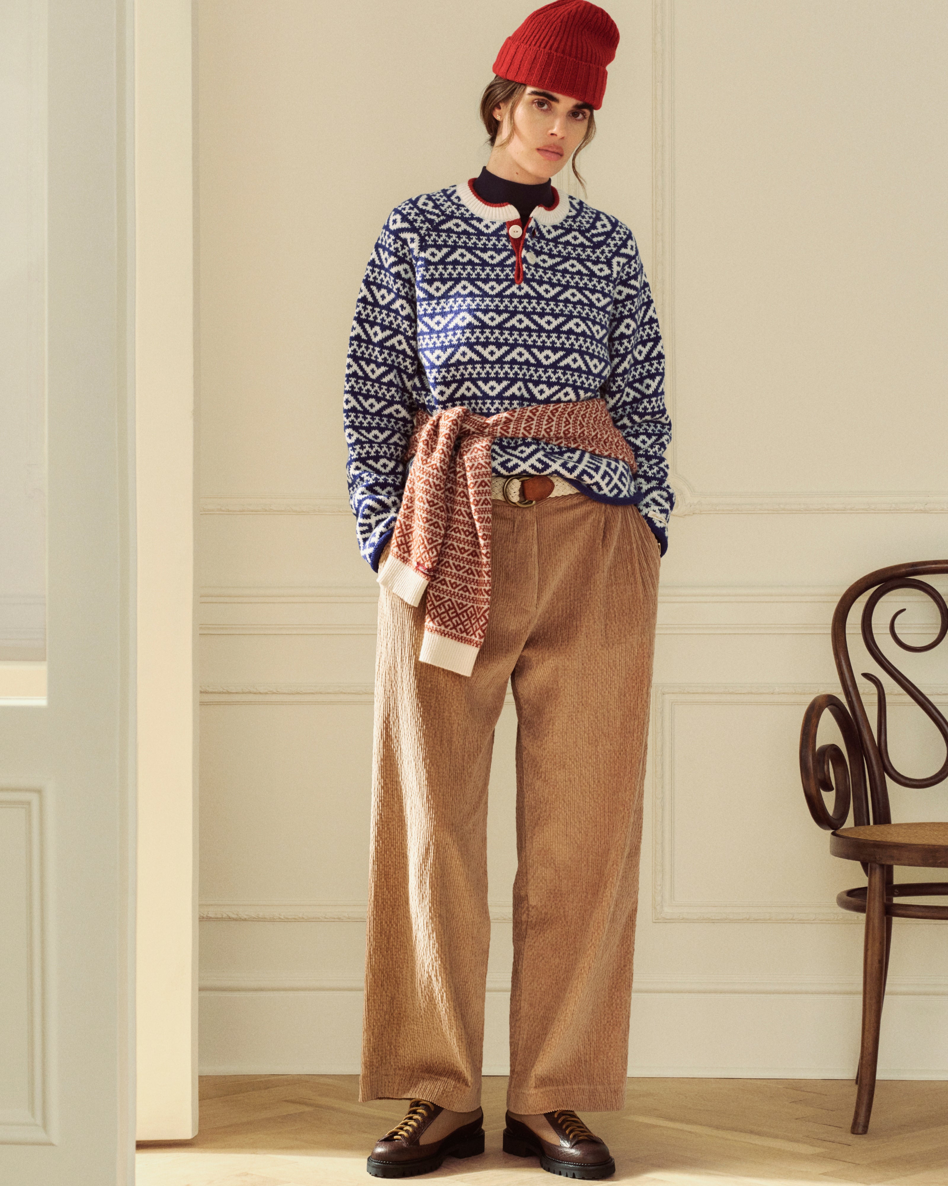 A person wearing a red beanie, a blue and white patterned sweater, and tan Double Pleated Corduroy Trouser.