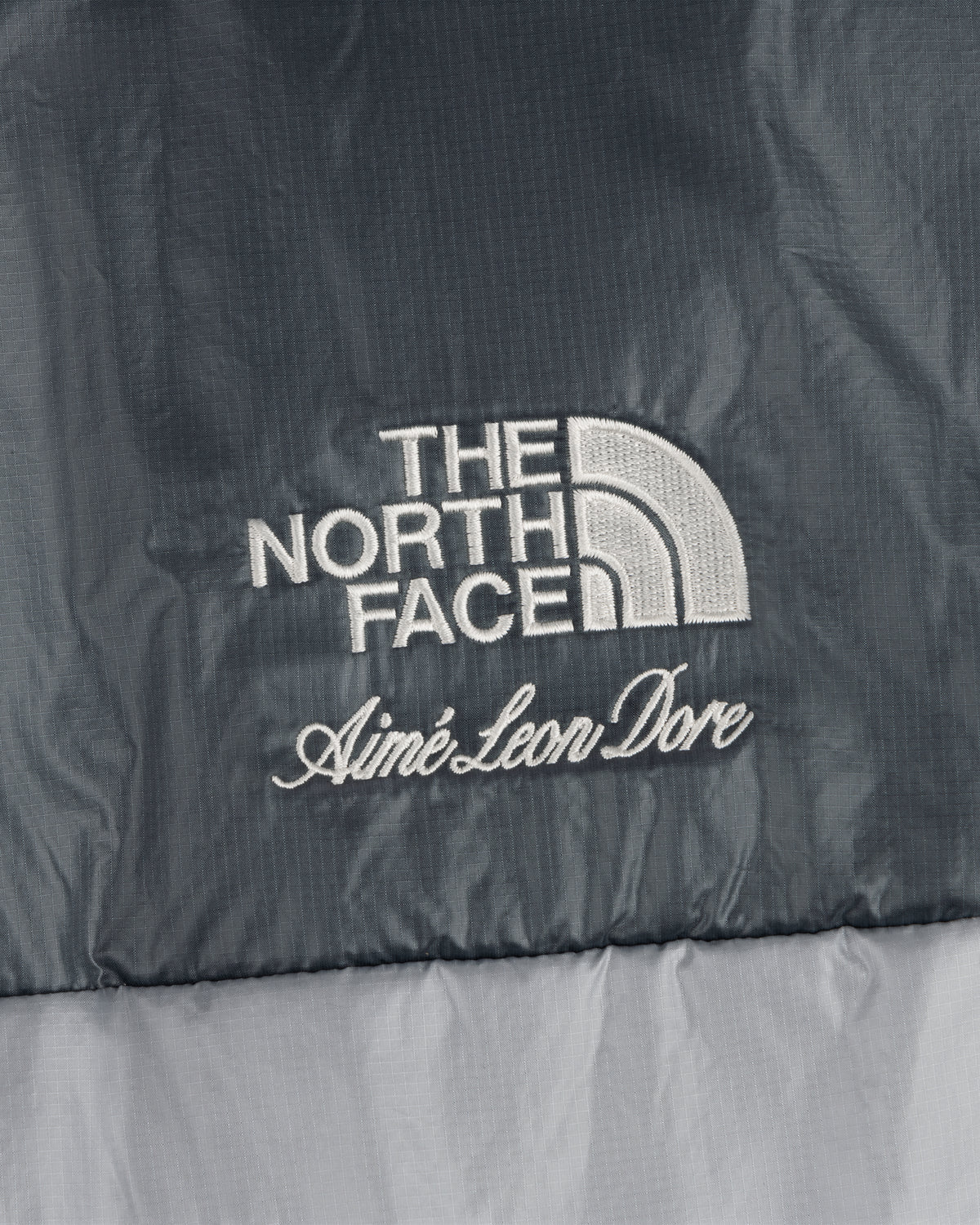 ALD / The North Face logos embroidered on the Reversible Pertex® Nuptse Jacket in two-tone gray fabric.