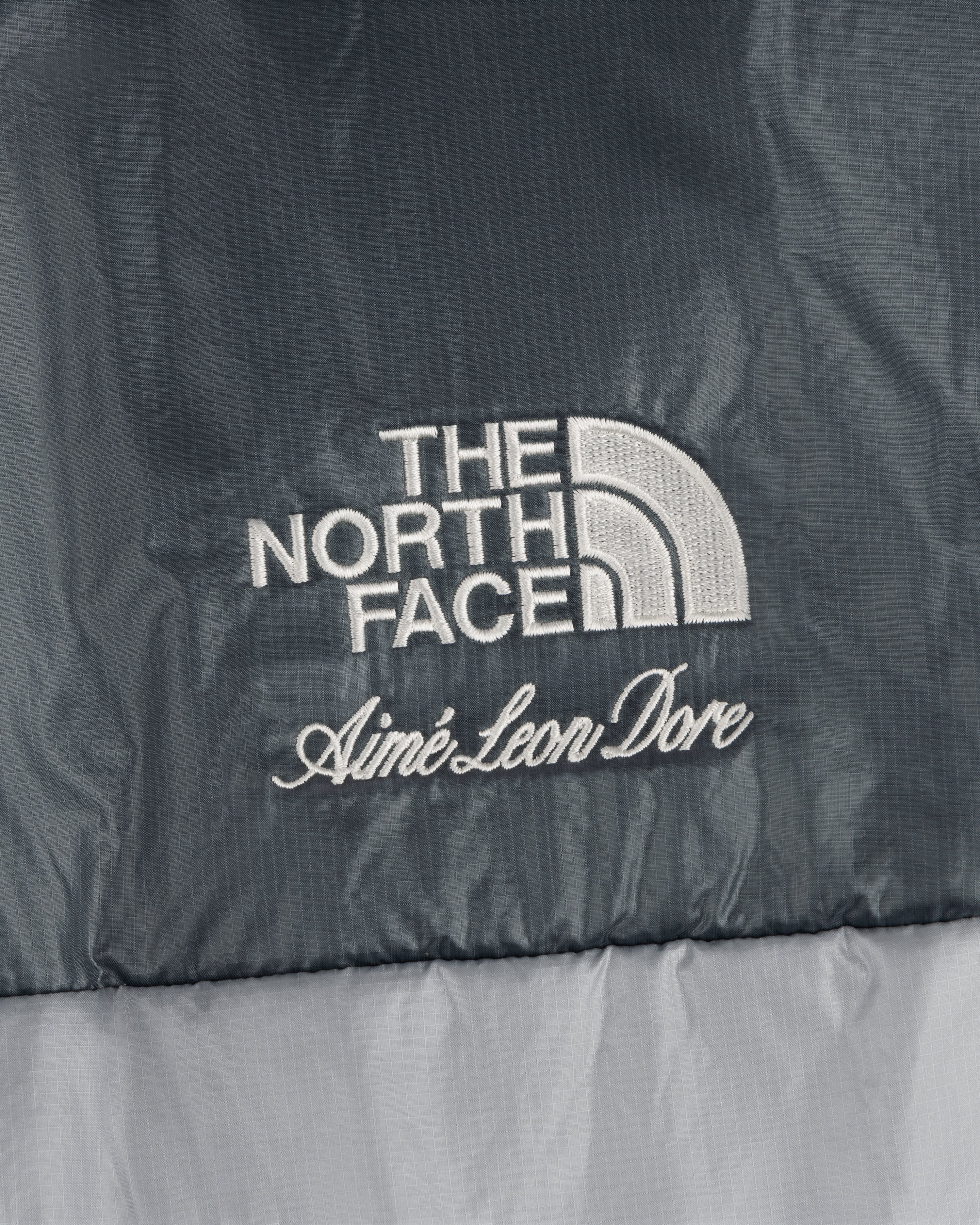 ALD / The North Face logos embroidered on the Reversible Pertex® Nuptse Jacket in two-tone gray fabric.