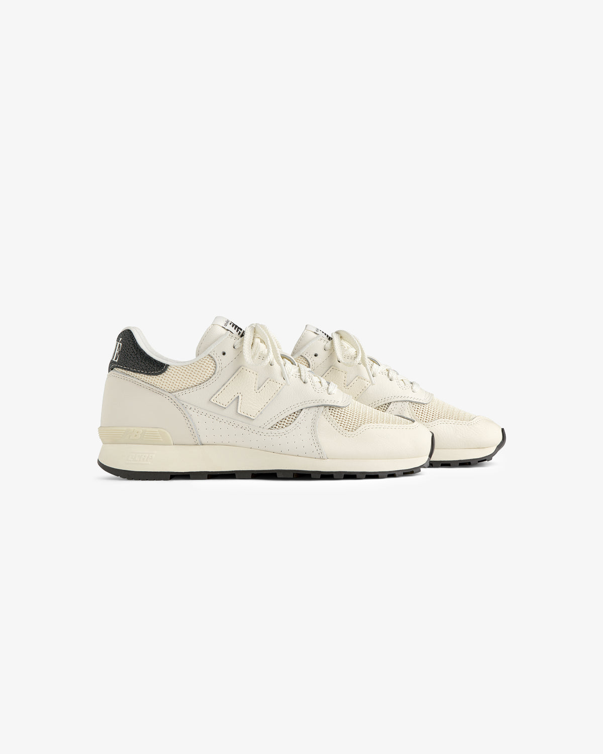 A pair of ALD / New Balance 475 sneakers in off-white with black heel accents on a plain white background.