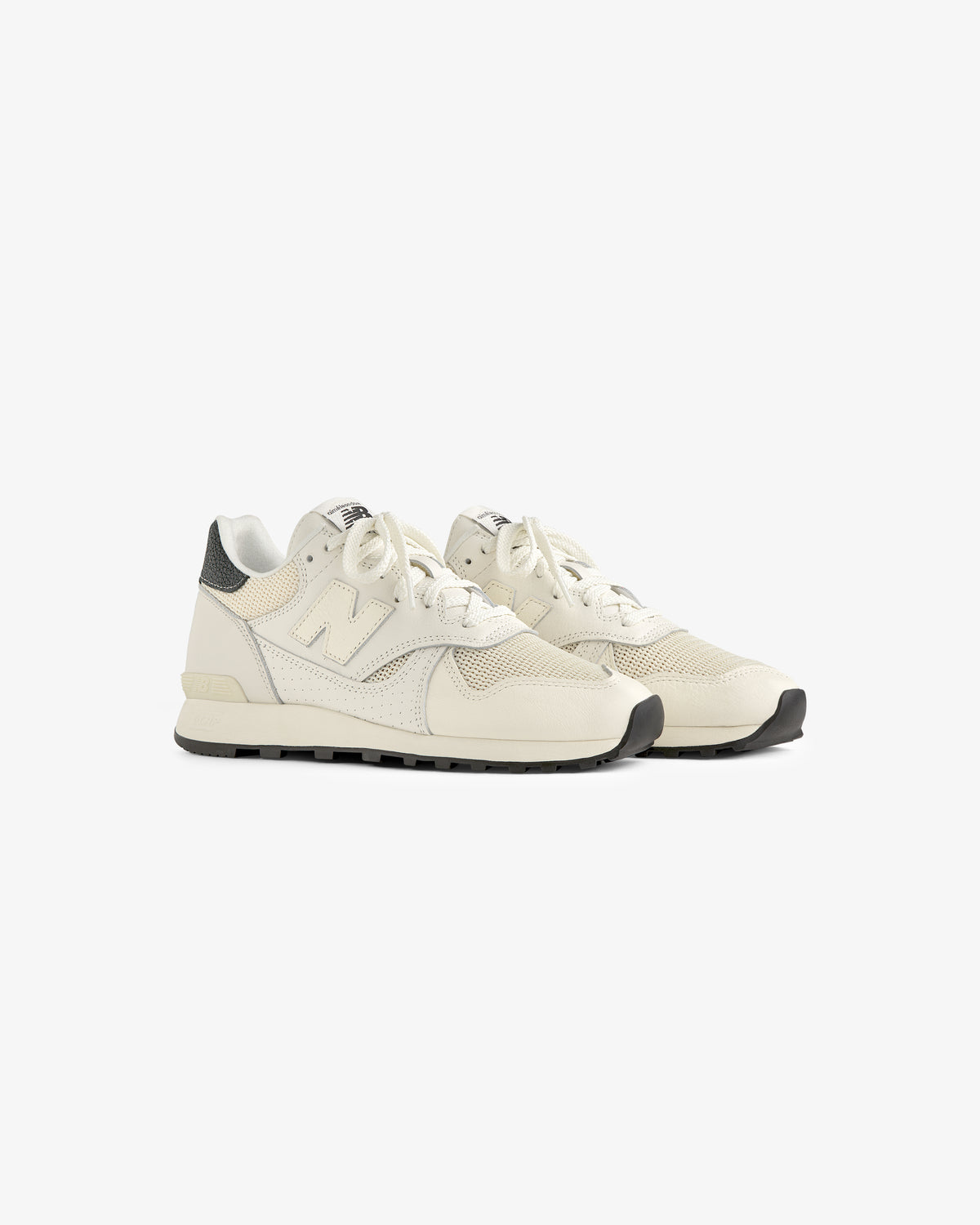 The ALD / New Balance 475 sneakers feature off-white mesh and leather, black soles, and heel accents on a white background.