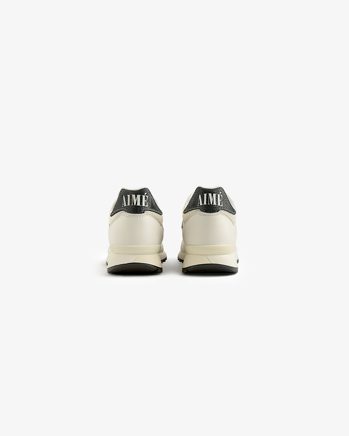 Back view of cream ALD / New Balance 475 sneakers with dark gray heels and AIMÉ on the heel tabs.