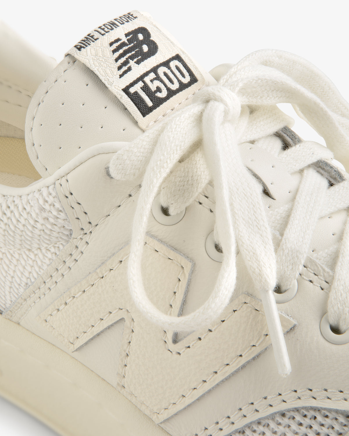 Close-up of white ALD / New Balance T500 Tennis Oxfords with visible logo and tied laces.