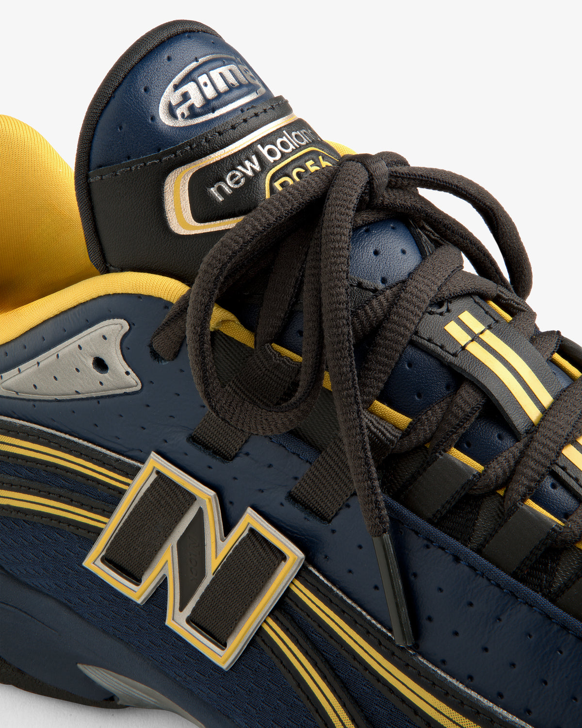 Close-up of a navy and yellow ALD / New Balance RC56 sneaker, highlighting the laces and logo details.