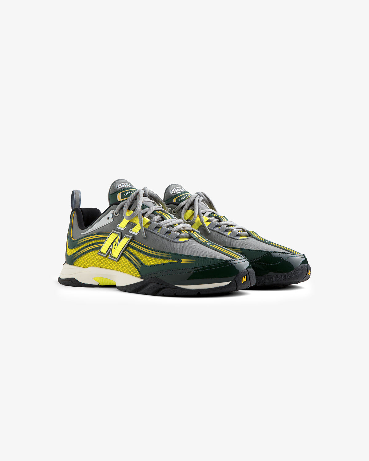 A pair of ALD / New Balance RC56 sneakers in green, yellow, and gray with white soles on a white background.