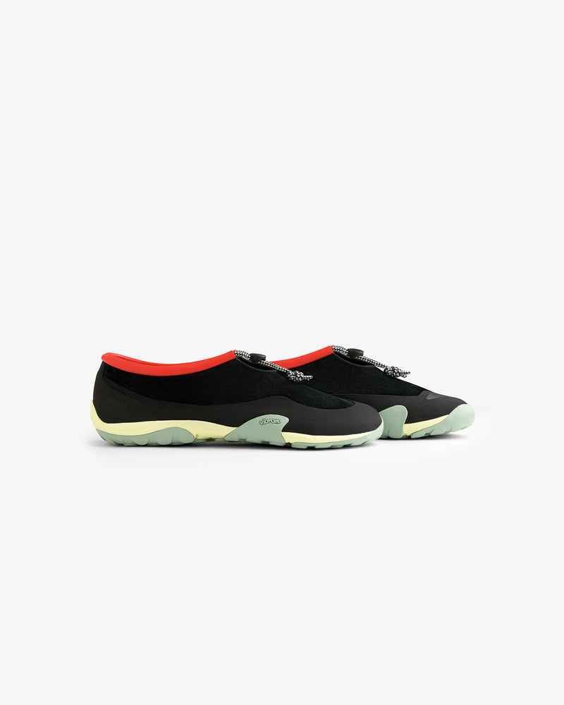 ALD / New Balance MT10T Sport Shoe: black slip-ons with light green soles, red interiors, and patterned laces.