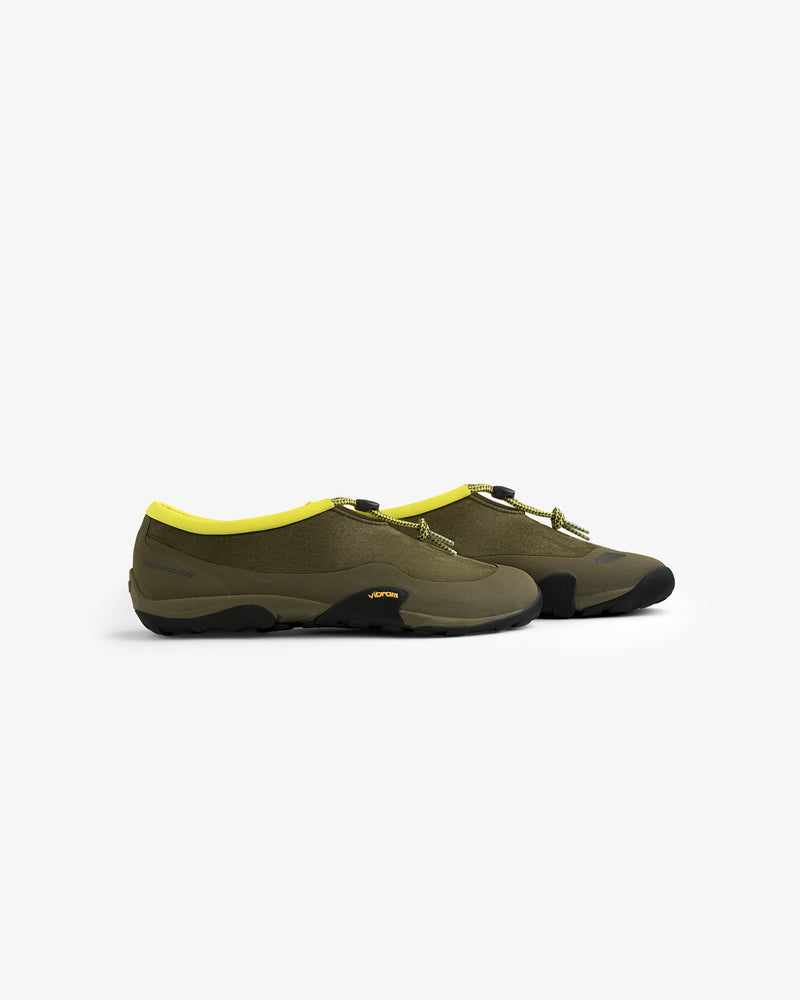 ALD / New Balance MT10T Sport Shoe in olive green with yellow lining, black soles, side view on white background.