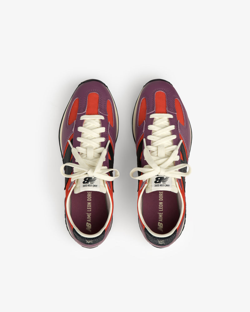 The ALD / New Balance 471 sneakers with purple, red, and black accents viewed from above on a white background.
