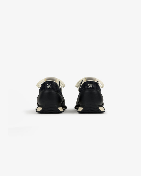 ALD / New Balance 471 black sneakers with white laces and soles, shown from the back on a plain white background.