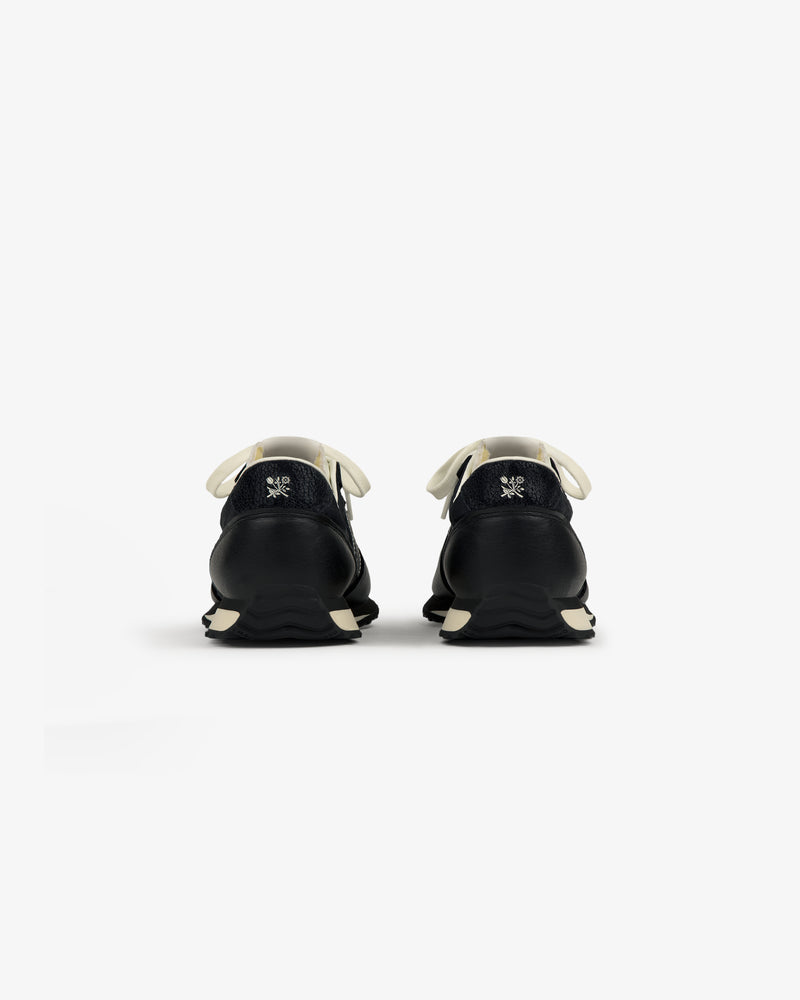 ALD / New Balance 471 black sneakers with white laces and soles, shown from the back on a plain white background.