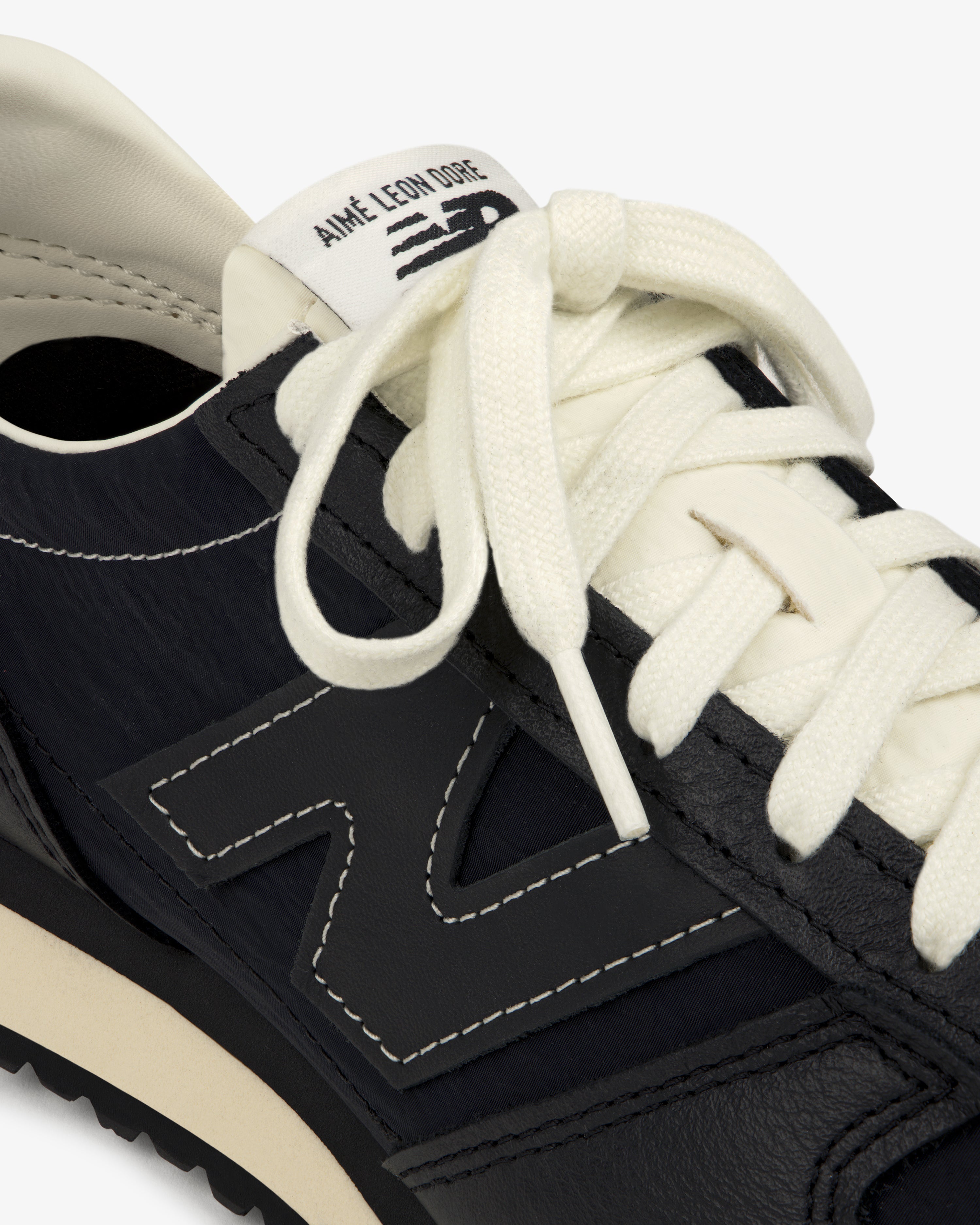 Close-up of a black ALD / New Balance 471 sneaker with white laces and Aimé Leon Dore branding on the tongue.