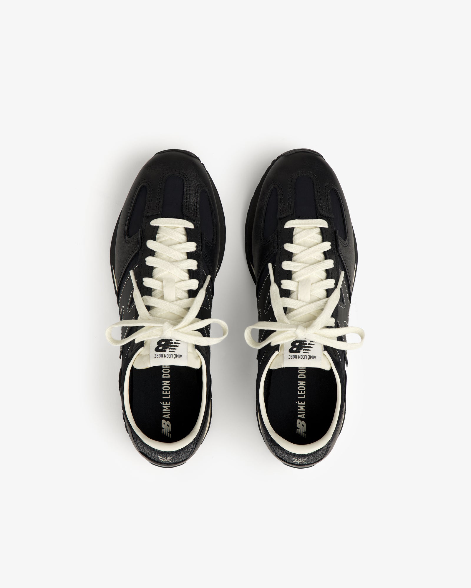 A pair of black ALD / New Balance 471 sneakers with white laces and branded text inside.