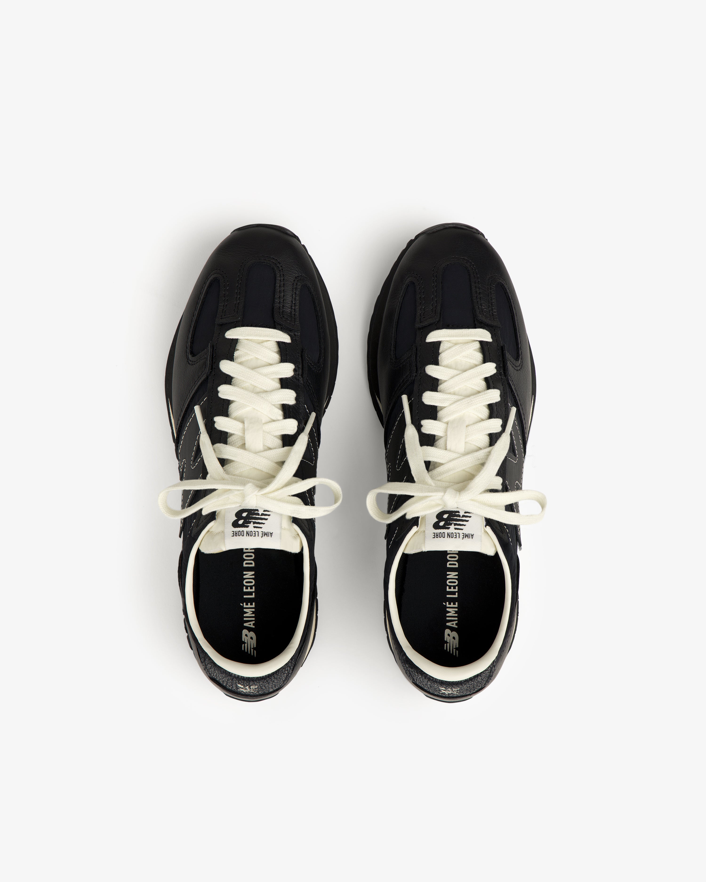 A pair of black ALD / New Balance 471 sneakers with white laces and branded text inside.