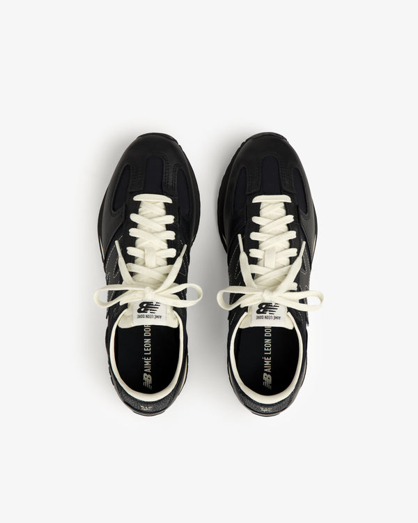 A pair of black ALD / New Balance 471 sneakers with white laces and branded text inside.