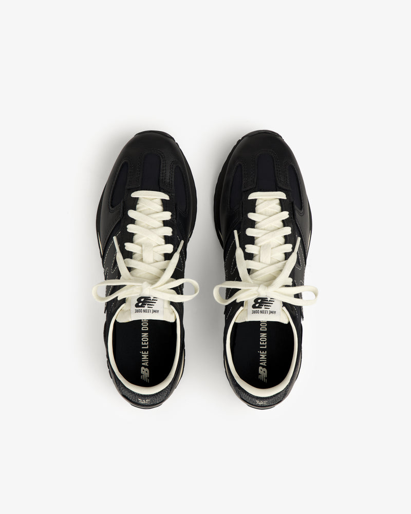 A pair of black ALD / New Balance 471 sneakers with white laces and branded text inside.