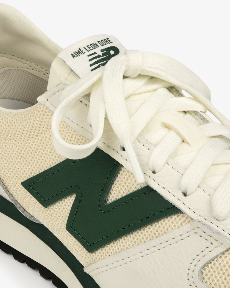 Close-up of a cream and green ALD / New Balance 471 sneaker with “Aimé Leon Dore” branding on the tongue.