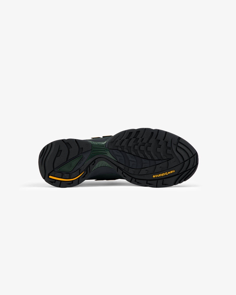 Black outsole with wavy tread and yellow logo on right heel of ALD / New Balance RC56 sneaker.