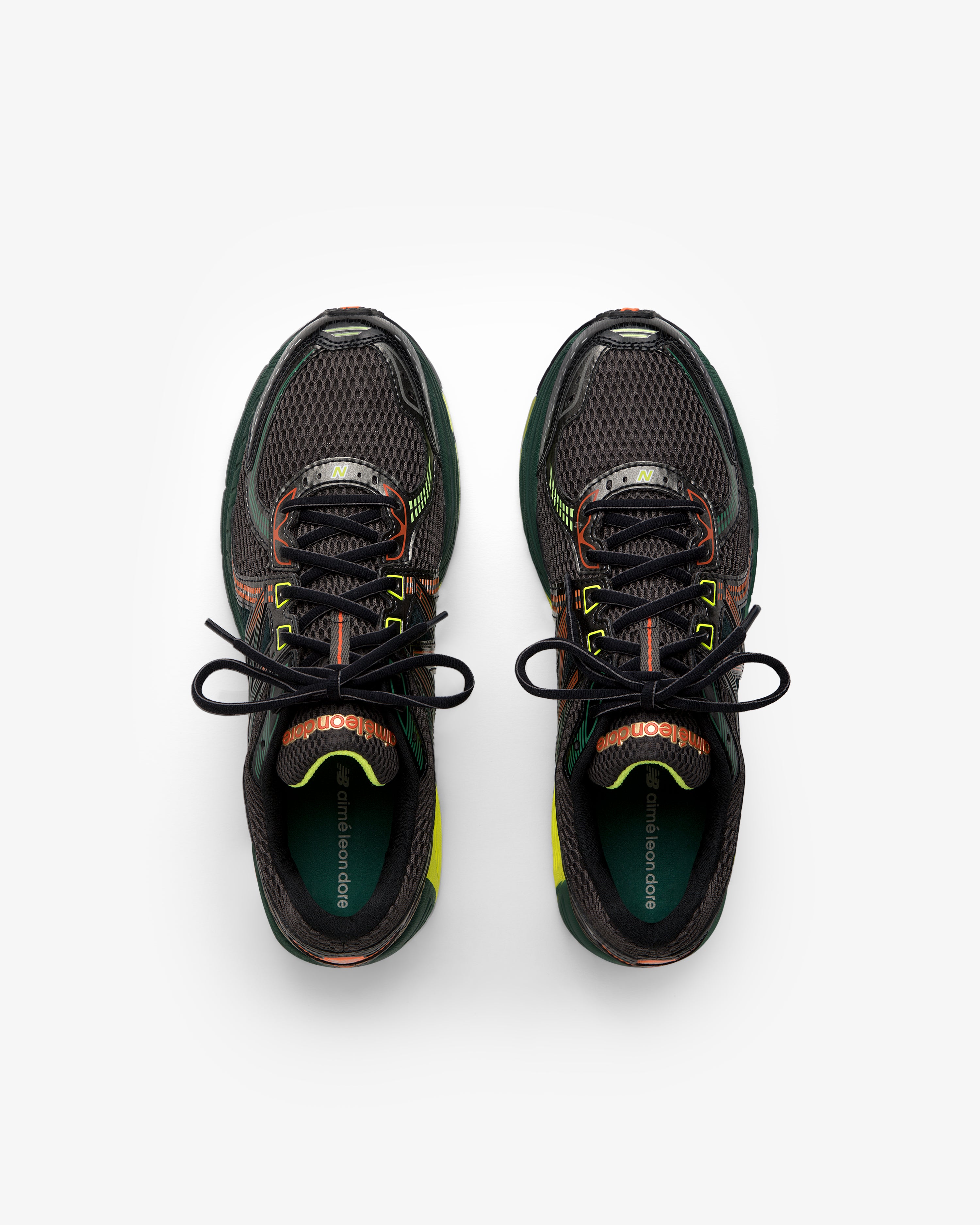 The ALD / New Balance 860v2 sneakers in black mesh with green and orange accents, shown from above on white.