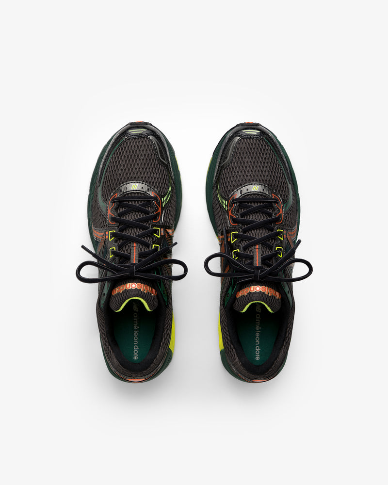 The ALD / New Balance 860v2 sneakers in black mesh with green and orange accents, shown from above on white.