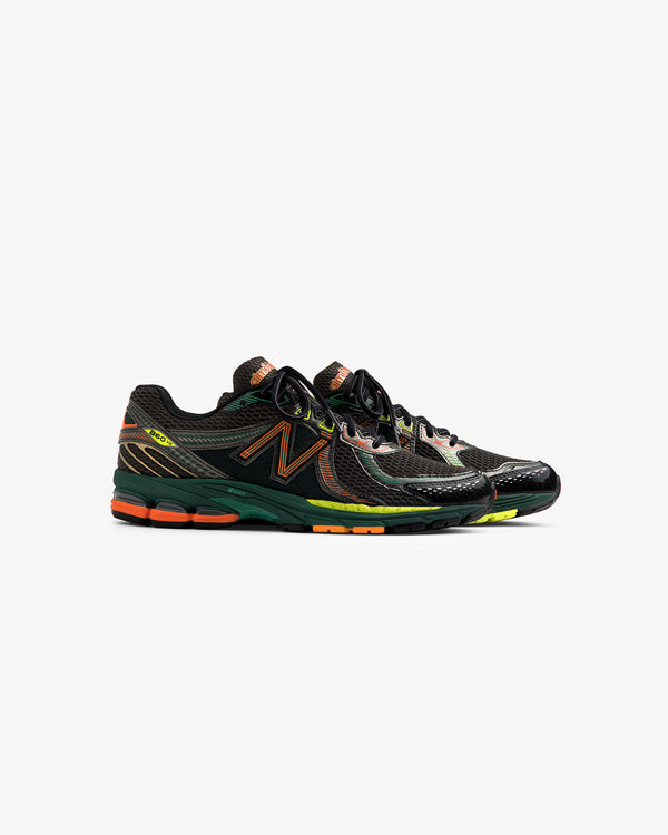 A pair of ALD / New Balance 860v2 sneakers in black with orange, green, and yellow accents on a white background.