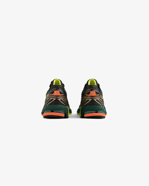 The ALD / New Balance 860v2 sneakers in black, green, and orange shown from the back on a white background.