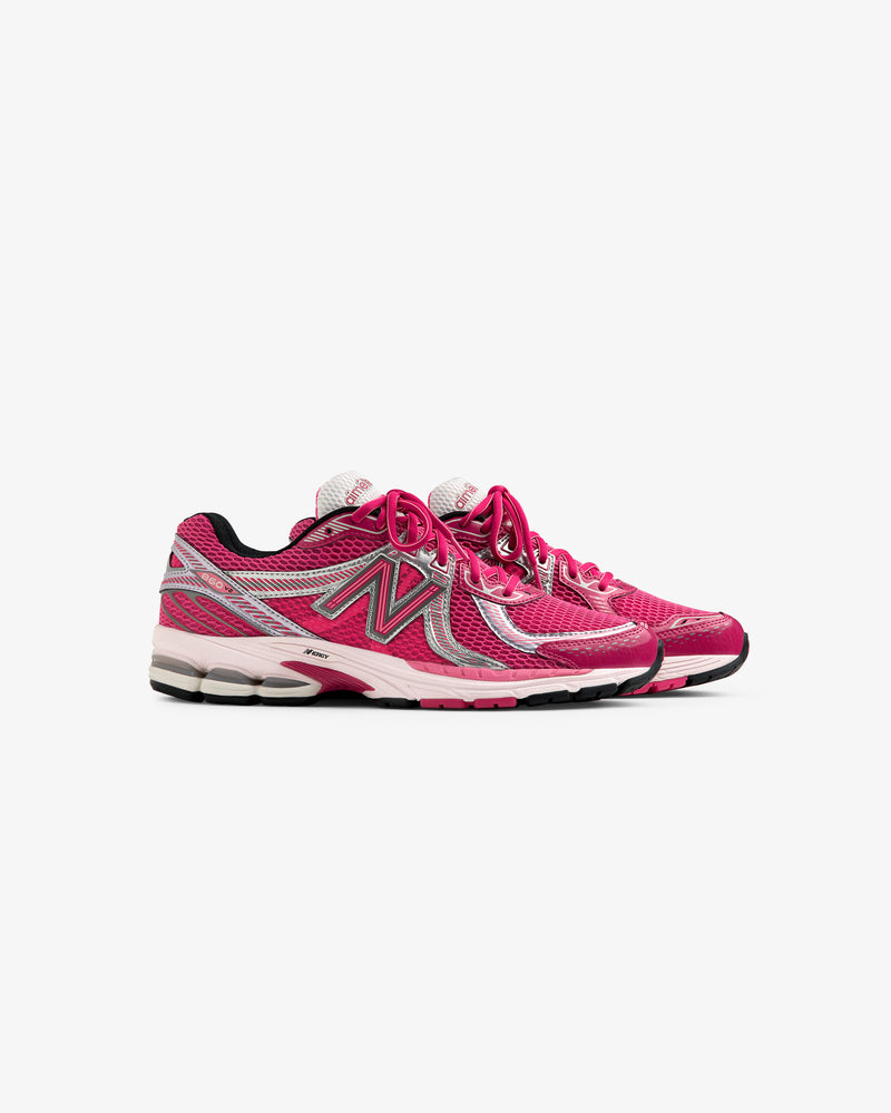 A pair of ALD / New Balance 860v2 pink and silver running shoes with white soles, side view on white background.