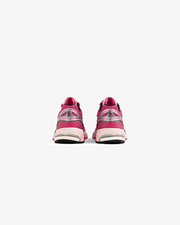 A pair of ALD / New Balance 860v2 pink sneakers seen from the back against a plain white background.