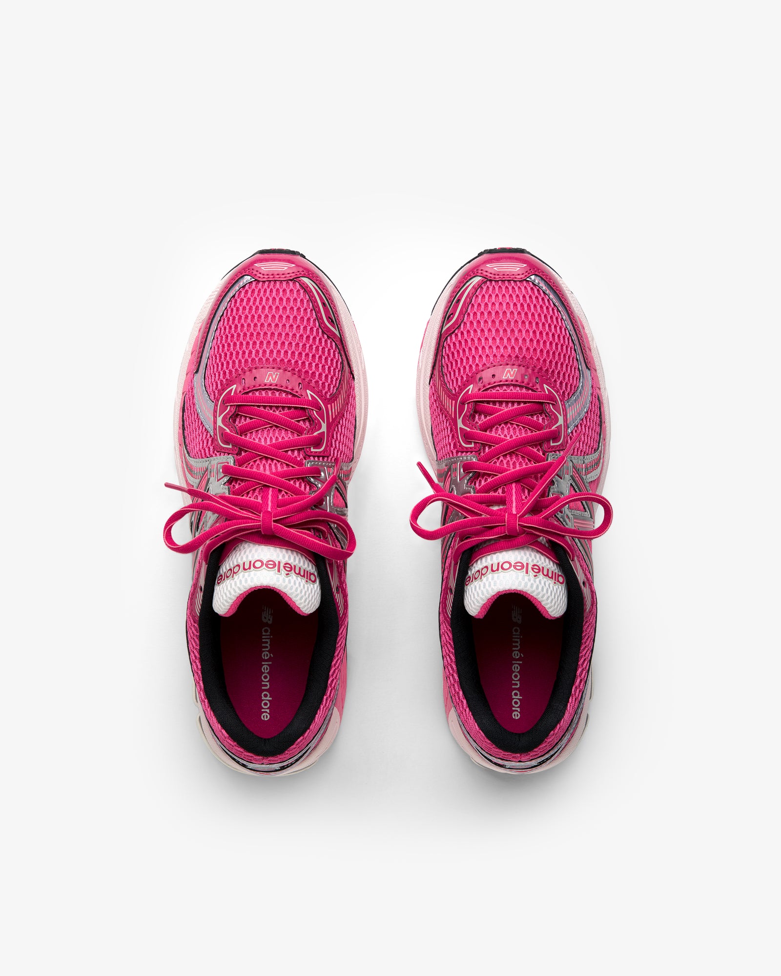A pair of ALD / New Balance 860v2 pink running shoes with laces, viewed from above on a white background.