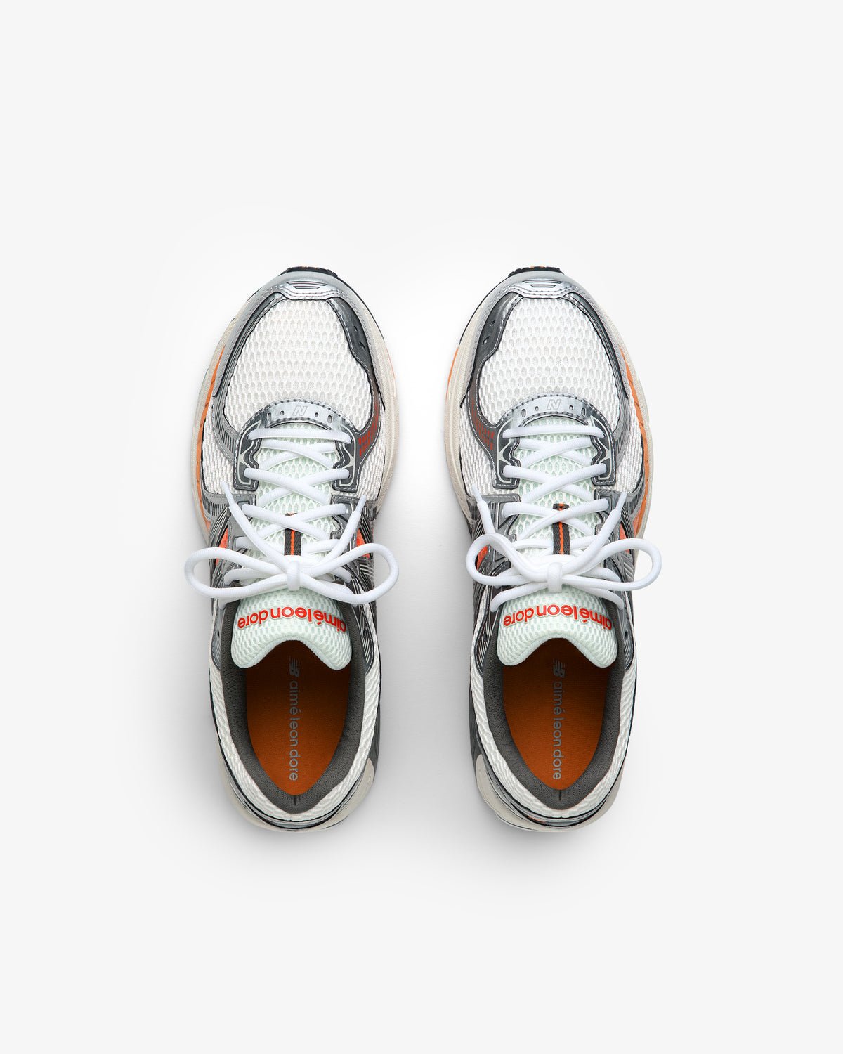 A pair of ALD / New Balance 860v2 sneakers in white, gray, and orange with white laces seen from above.
