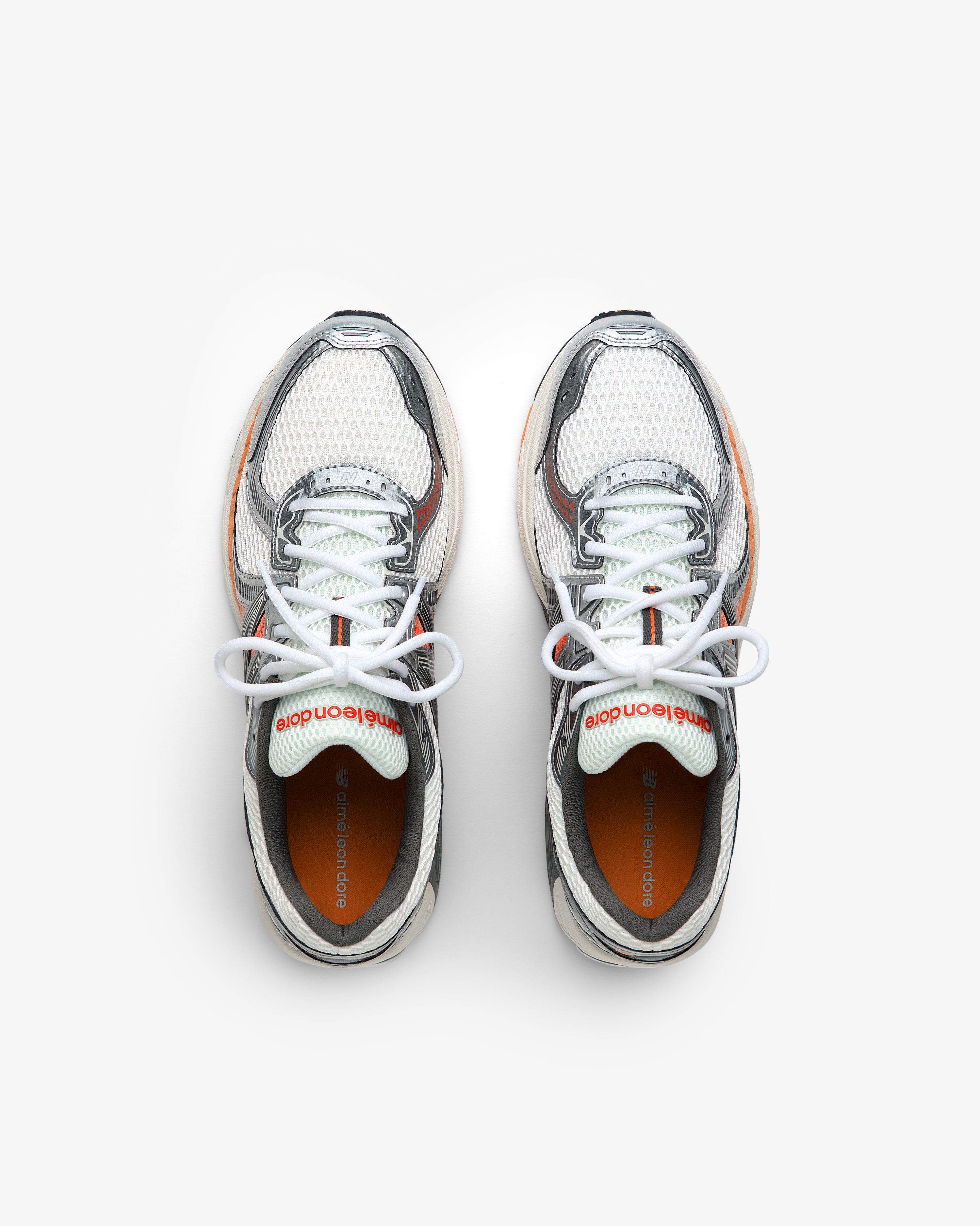 A pair of ALD / New Balance 860v2 sneakers in white, gray, and orange with white laces seen from above.