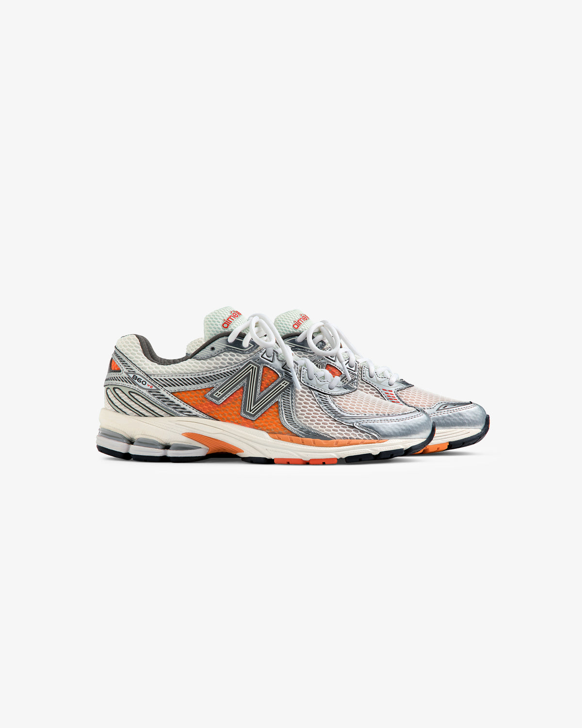 Pair of ALD / New Balance 860v2 running shoes with white, grey, orange, and black details on a white background.