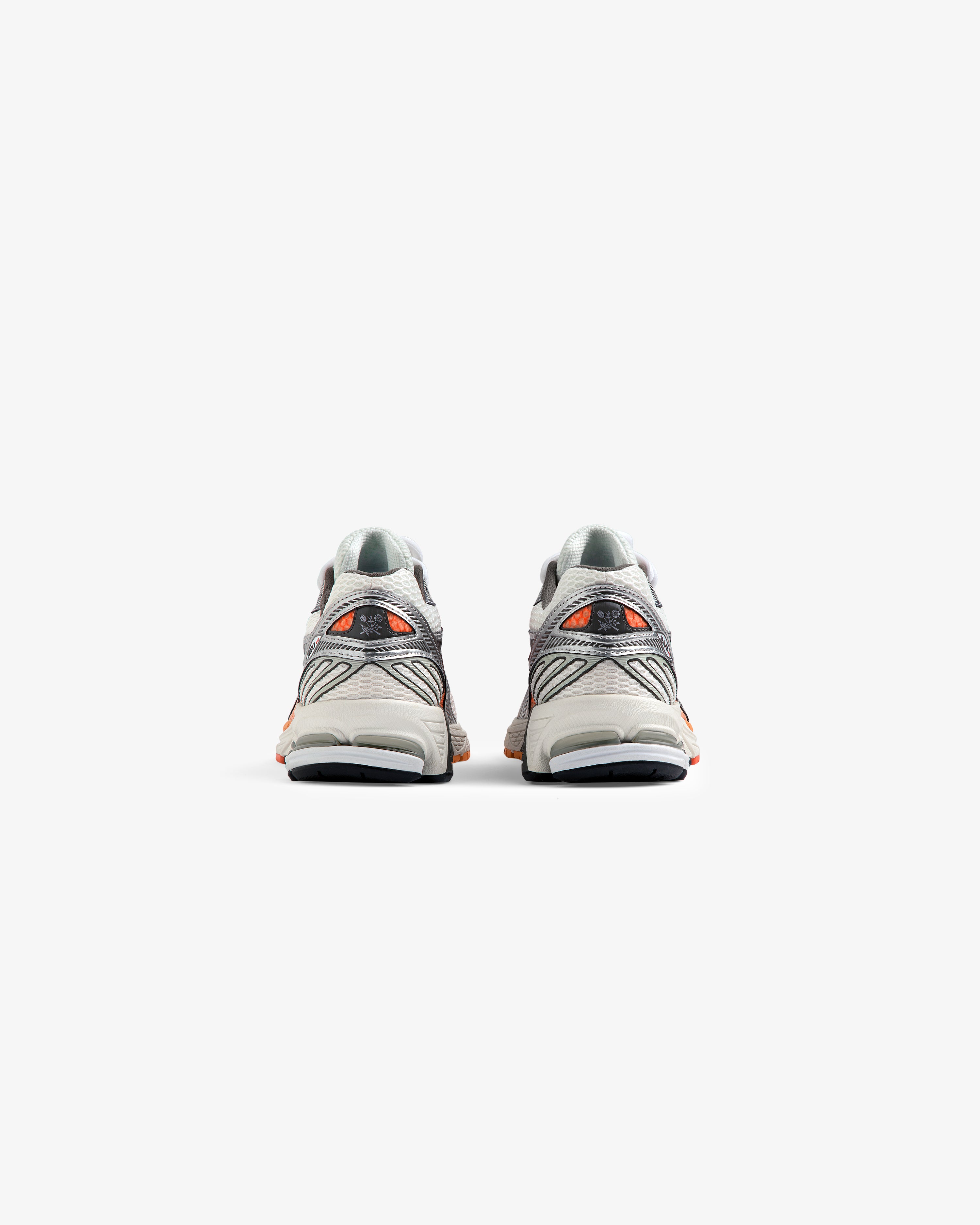 A pair of ALD / New Balance 860v2 sneakers in gray and orange, viewed from the back on a white background.