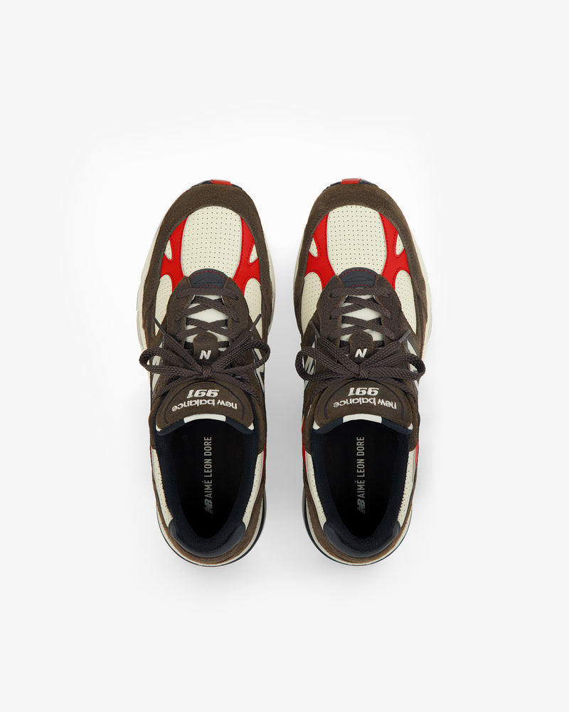 A pair of brown, red, and white ALD / New Balance Made in UK 991 sneakers viewed from above on a white background.