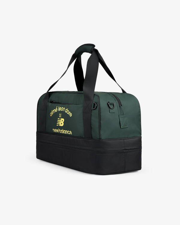 ALD / New Balance Travel Duffle Bag in dark green and black with yellow logos on the side.