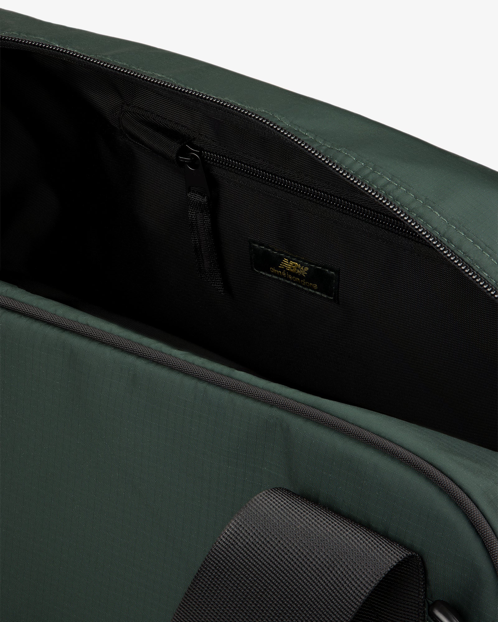 Close-up of the open ALD / New Balance Travel Duffle Bag showing a zippered pocket and black strap inside.