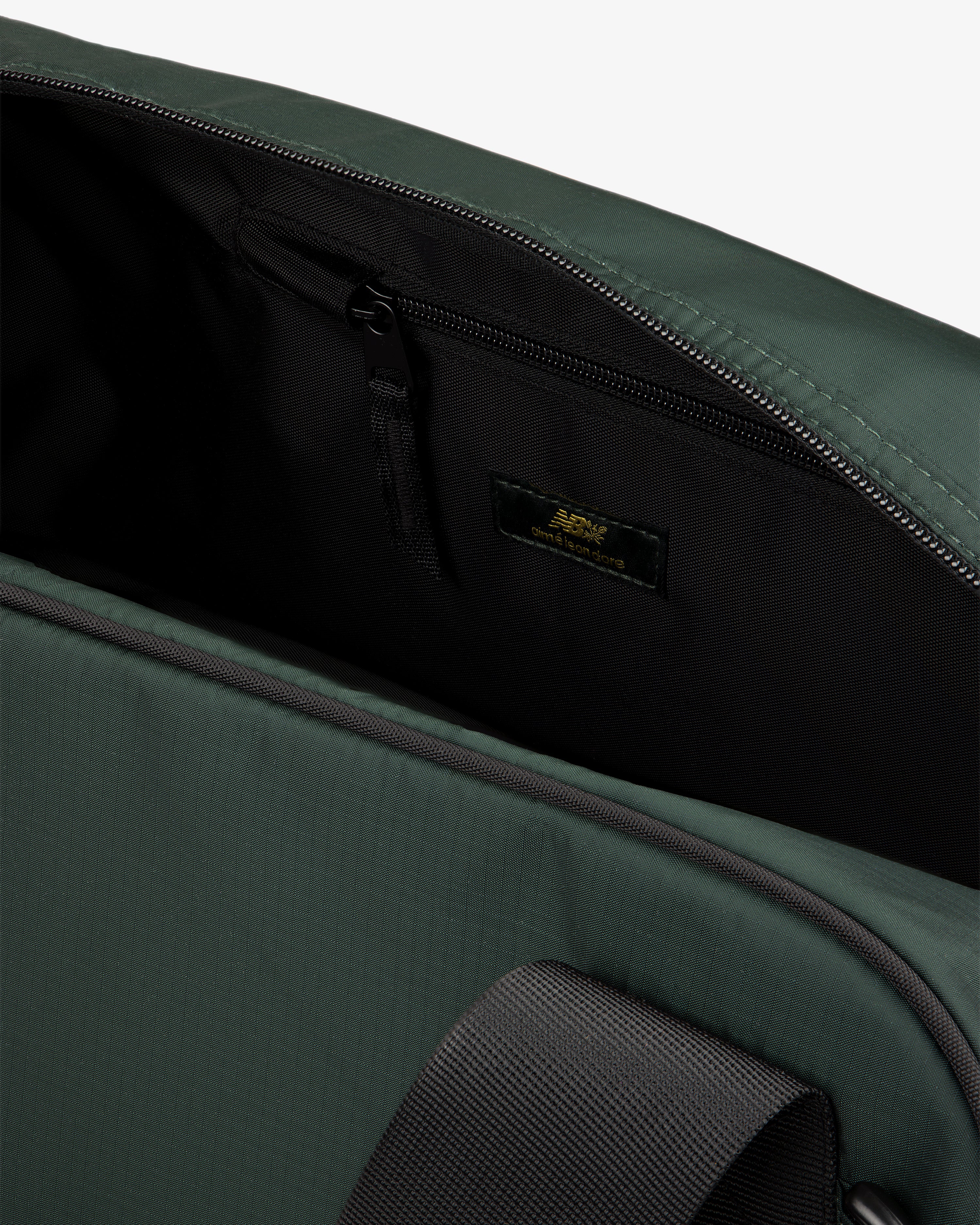 Close-up of the open ALD / New Balance Travel Duffle Bag showing a zippered pocket and black strap inside.